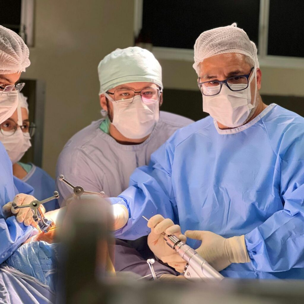 A surgical team in an operating room, fully outfitted in sterile gowns, masks, and caps, performing a procedure with specialized medical equipment.